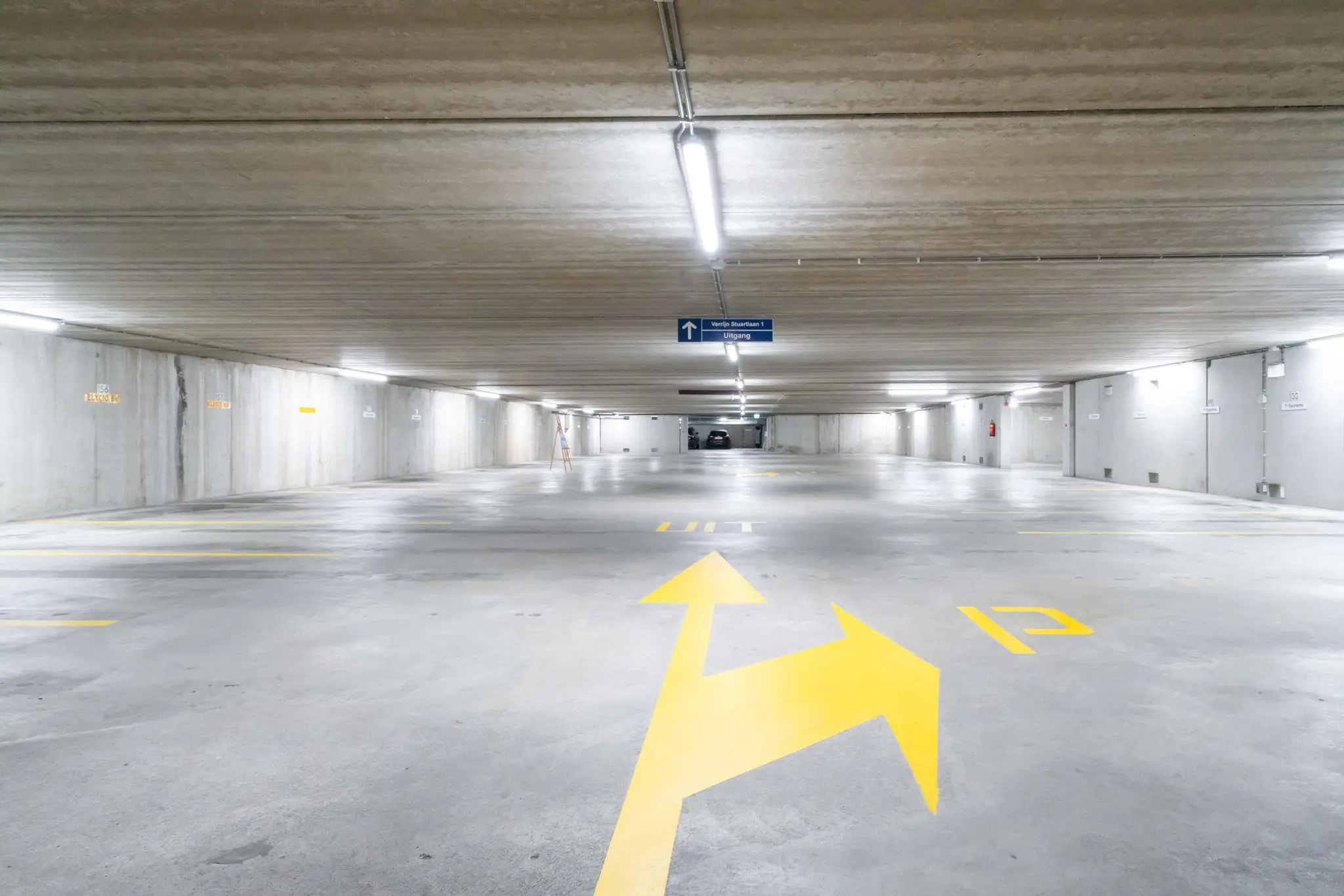 Ondergrondse parkeergarage aan de De Bruyn Kopsstraat met gele wegmarkeringen en richtingaanwijzer naar de uitgang.